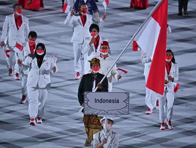 Kontingen Indonesia mengikuti defile dalam pembukaan Olimpiade Tokyo 2020, di Stadion Nasional Jepang, Tokyo, Jumat malam (23/7/2021). Upacara pembukaan Olimpiade Tokyo yang berlangsung dalam era pandemi, dan digelar tanpa penonton. (Ben STANSALL/AFP)