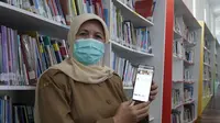 Kepala Dinas Perpustakaan dan Kearsipan Kabupaten Garut, Lisnawati tengah menunjukan penggunaan aplikasi online i-Bagendit bagi masyarakat di masa pandemi. (Liputan6.com/Jayadi Supriadin)