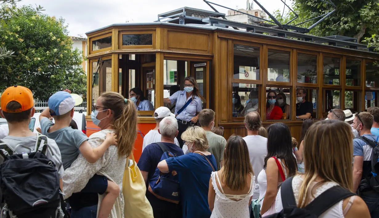 Orang-orang menaiki trem Soller-Puerto de Soller di Soller di Pulau Balearic Spanyol Mallorca (14/7/2021). Kereta dan lokomotif mempertahankan desain aslinya, dengan pemeliharaan dan perbaikan dilakukan di bengkel kereta api itu sendiri, dengan menghormati model awal. (AFP/Jaime Reina)