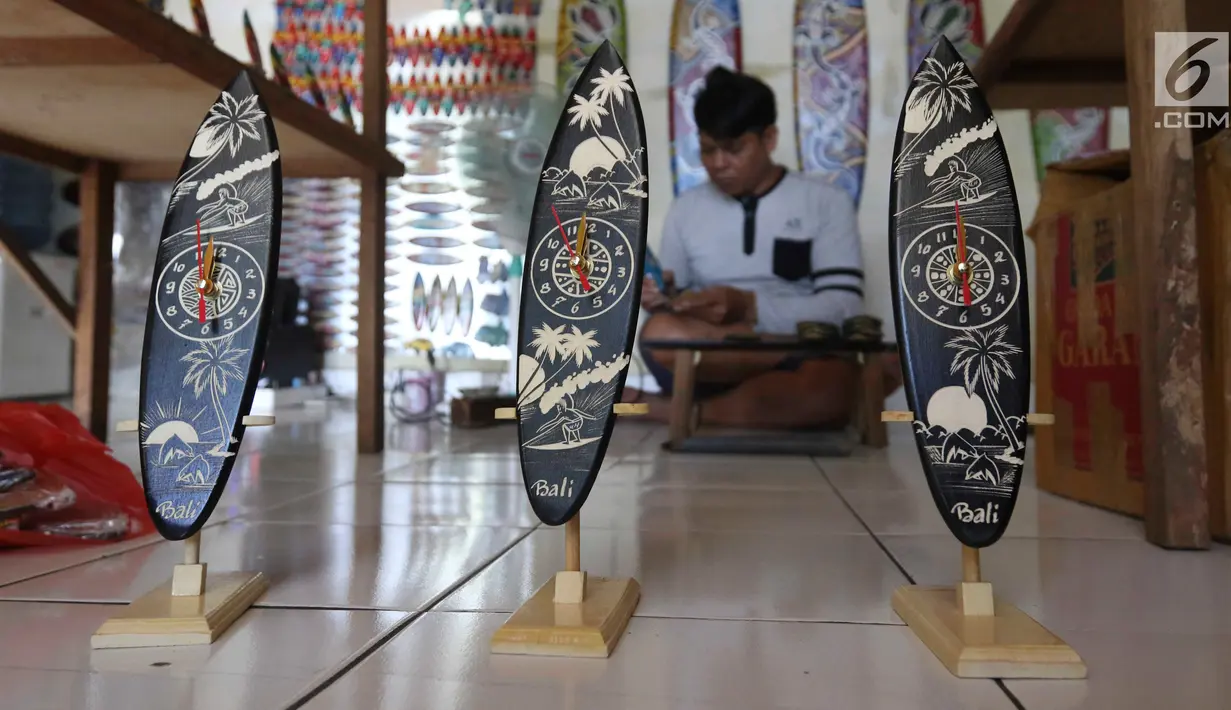 Pengrajin membuat sovenir papan seluncur di Bali, Senin (15/10). KUR yang disediakan pemerintah untuk sektor pariwisata sebagai upaya pengembangan destinasi di Indonesia. (Liputan6.com/Angga Yuniar)