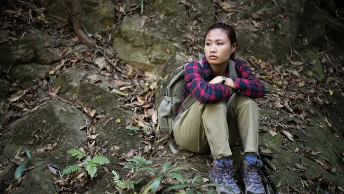 Seorang perempuan sedang duduk dan beristirahat saat mendaki gunung (Foto Dok: Freepik/jcomp)