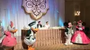Pasangan pengantin Sandra dan Harvey melakukan potong kue pengantin yang disaksikan oleh para tamu undangan dan didampingi karakter kartun Disney tersebut. (Facebook/Ary Bakri)