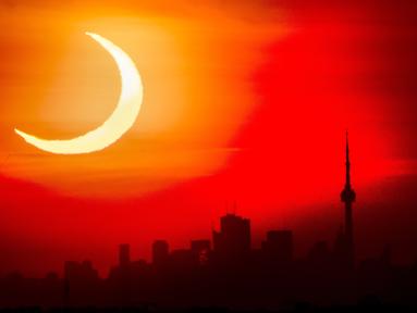 Gerhana matahari cincin muncul di atas cakrawala Toronto, Kamis (10/6/2021). Fenomena gerhana matahari cincin jatuh pada 10 Juni 2021. Gerhana matahari cincin menjadi fenomena yang dinanti setelah gerhana Bulan total pada 26 Mei 2021 lalu.  (Frank Gunn/The Canadian Press via AP)