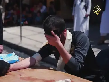 Gambar dari sebuah video milik ISIS menunjukkan seorang pelaku kejahatan menutup matanya jelang eksekusi hukuman potong tangan oleh ISIS di Distrik Al-Karama, Mosul, Irak. Potong tangan merupakan hukum syariah yang diterapkan ISIS. (Handout via Reuters)