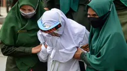 Polisi syariat membawa terpidana kasus zina untuk menjalani hukuman cambuk di halaman Masjid Al-Munawarah, Kota Jantho, Aceh Besar,  Jumat (9/4/2020). Pasangan terpidana yang terbukti melanggar Syariat Islam dalam kasus zina itu masing masing menjalani sebanyak 100 cambuk. (CHAIDEER MAHYUDDIN/AFP)