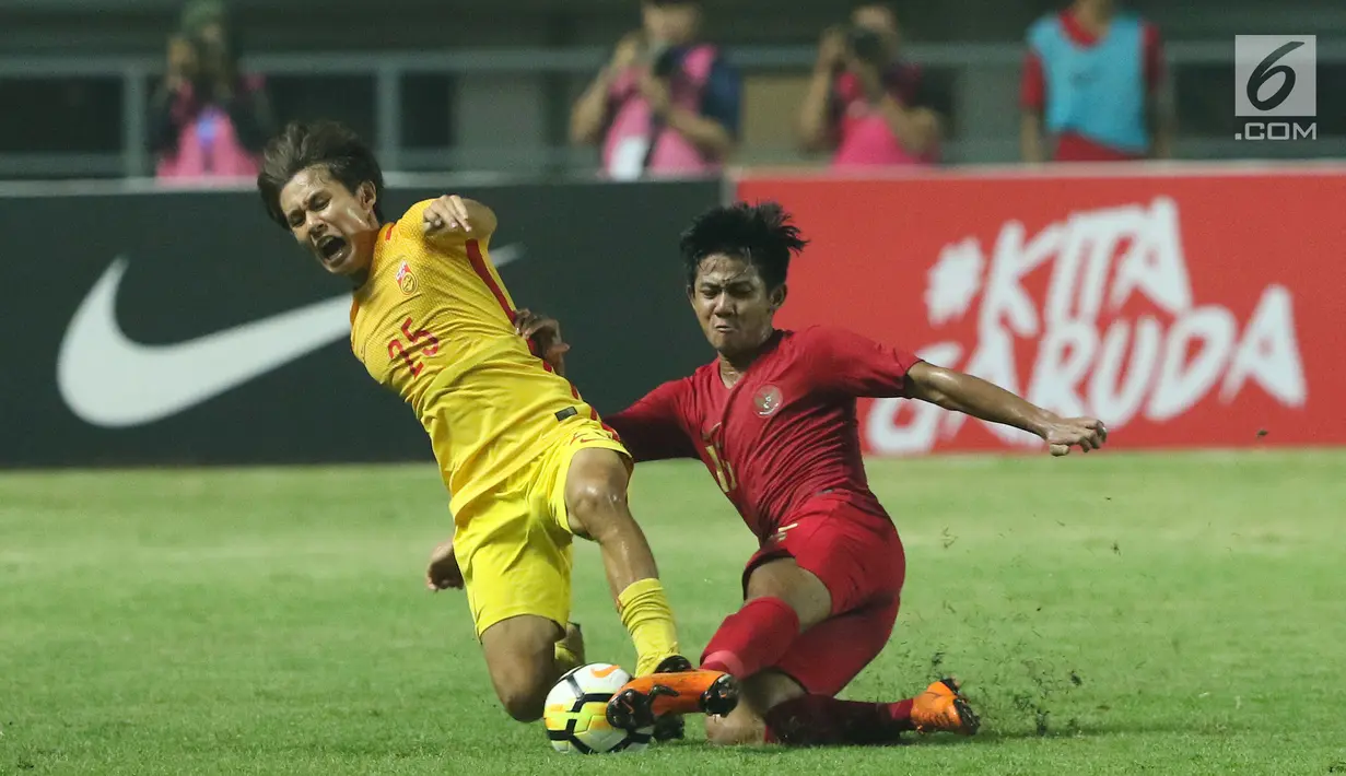 Bek Timnas Indonesia U-19, Firza Andika (kanan) berebut bola dengan pemain China U-19, Qinhan Sun pada laga PSSI 88th U-19 International Tournament di Stadion Pakansari, Cibinong, Selasa (25/9). Indonesia kalah 0-3. (Liputan6.com/Helmi Fithriansyah)