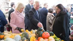 Pangeran Charles bersama istrinya, Duchess of Cornwall Camilla berbincang dengan pedagang ketika mengunjungi Swiss Cottage Farmers Market di London utara, Rabu (6/11/2019). Kunjungan Charles dan Camila untuk memperingati ulang tahun ke-20 pasar tersebut. (Eddie Mulholland / POOL / AFP)