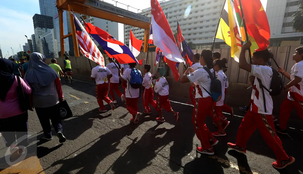 Sejumlah remaja membawa bendera negara-negara peserta Sea Games di Jakarta, Minggu (30/4). Kirab itu berlangsung guna menyambut Sea Games Kuala Lumpur 2017. (Liputan6.com/Johan Tallo)