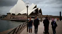 Orang-orang mengunjungi Opera House di Sydney pada Rabu (30/12/2020). Pihak berwenang berupaya menekan klaster kasus virus corona Covid-19 yang terus bertambah di kota terpadat di Australia tersebut. (Saeed KHAN / AFP)