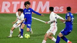 Pemain Real Madrid, Alvaro Odriozola, berebut bola dengan pemain Getafe, Marc Cucurella, pada laga Liga Spanyol di Stadion Alfonso Perez, Senin (19/4/2021). Kedua tim bermain imbang 0-0. (Photo by PIERRE-PHILIPPE MARCOU / AFP)