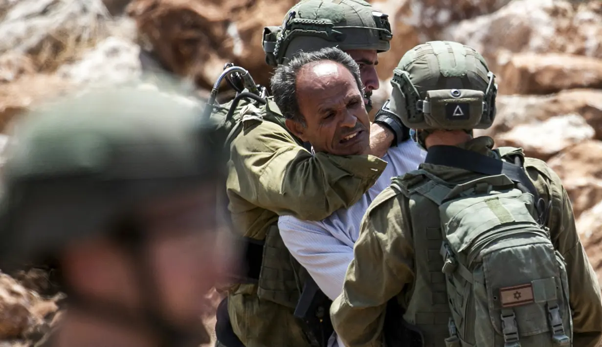 Tentara Israel mengamankan seorang pengunjuk rasa Palestina yang memprotes pembukaan lahan untuk permukiman Israel di dekat Desa Shoufah, wilayah Tepi Barat (20/8/2020). (AFP/JAAFAR ASHTIYEH)