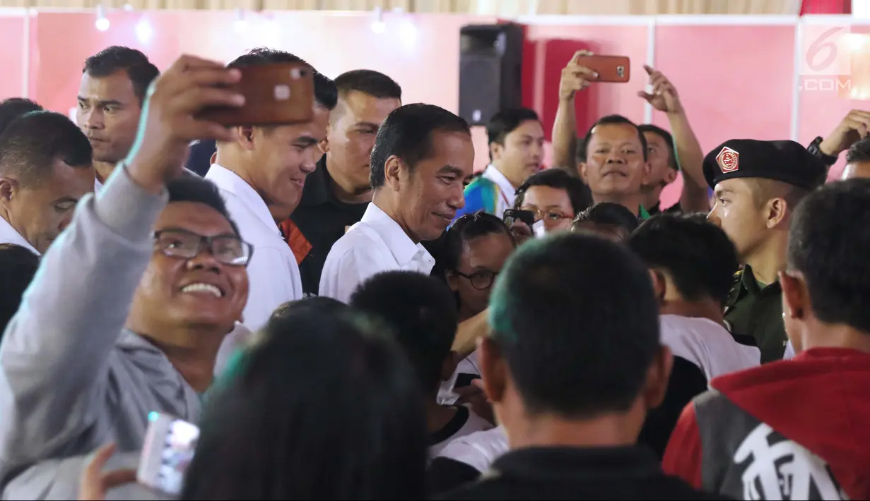 Presiden RI, Joko Widodo (tengah) dikerumuni penonton usai menyaksikan laga atlet para powerlifting Indonesia di kelas Womens Up 73 dan 79kg Asian Para Games 2018 di Jakarta, Rabu (10/10). (Liputan6.com/Helmi Fithriansyah)