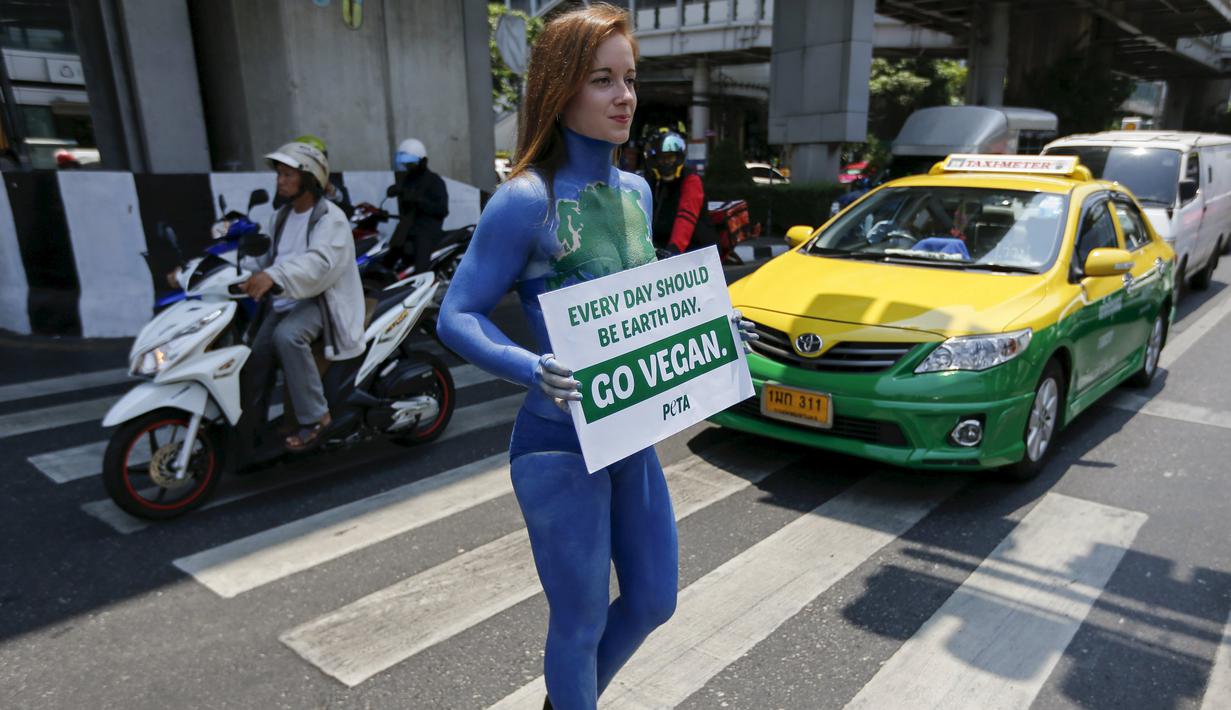Seorang wanita anggota PETA saat melakukan aksi untuk mempromosikan veganisme di Bangkok tanggal 21 April 2016. Wanita ini mewarnai sekujur tubuhnya dengan cat sambil membawa papan bertulis "Go Vegan".(REUTERS / Jorge Silva)