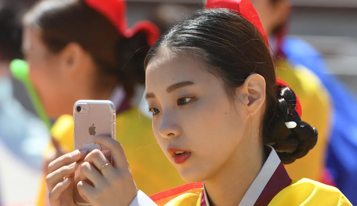 Seorang gadis muda Korea Selatan bermain ponsel selama upacara Coming of Age Day di desa Hanan Namsan di Seoul (21/5). Di usia 19 tahun, mereka diperbolehkan merokok, mengonsumsi minuman beralkohol, dan mengikuti pemilihan umum. (AFP Photo/Jung Yeon-je)