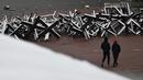 Pejalan kaki melewati konstruksi antitank yang tertutup salju setelah salju pertama turun musim ini di Kiev, Ukraina, 17 November 2022. Salju pertama musim ini turun di tengah invasi Rusia ke Ukraina. (Sergei SUPINSKY/AFP)