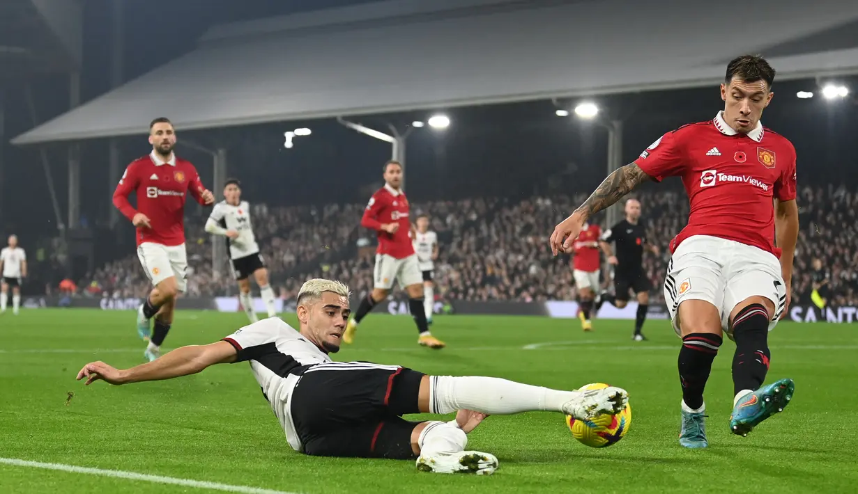 Gelandang Fulham Andreas Pereira (tengah) bersaing dengan bek Manchester United (MU) Lisandro Martinez pada pekan ke-16 Liga Inggris 2022/2023 di Craven Cottage, London, Minggu (13/11/2022).  Adapun Fulham tertahan di peringkat kesembilan dengan 19 poin dari 15 pertandingan.  (Photo by Glyn KIRK / AFP)