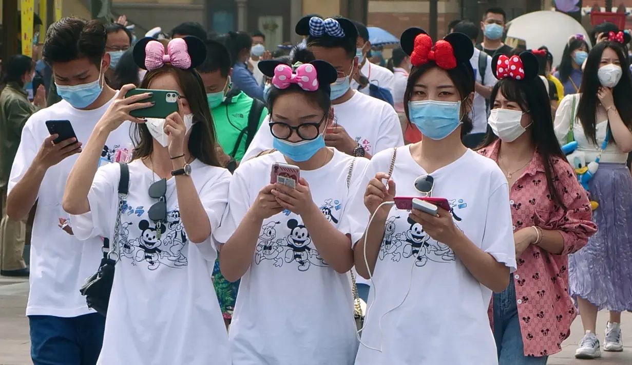 Wisatawan mengenakan masker saat mengunjungi taman hiburan Disneyland, Shanghai, China, Senin (11/5/2020). Jumlah orang yang naik wahana permainan dibatasi dan tempat duduknya dibuat berjarak. (AP Photo/Sam McNeil)