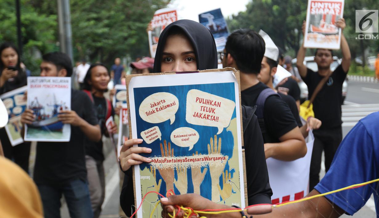 Massa yang tergabung dalam Koalisi Selamatkan Teluk Jakarta menggelar aksi jalan mundur menuju Balai Kota di Jakarta, Senin (24/6). Dalam aksinya mereka meminta kepada Gubernur DKI Jakarta untuk mencabut kembali keputusan penerbitan IMB di Pulau C dan D reklamasi Teluk Jakarta. (Liputan6.com/Angga Y