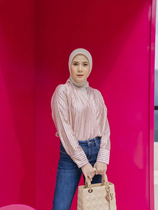 Cynthia Ramlan tampil kasual dengan kemeja satin beige dengan jeans. Ia pun mengenakan hijab dan menjinjing tas dengan warna senada [Barbie x Ayu Lestari]