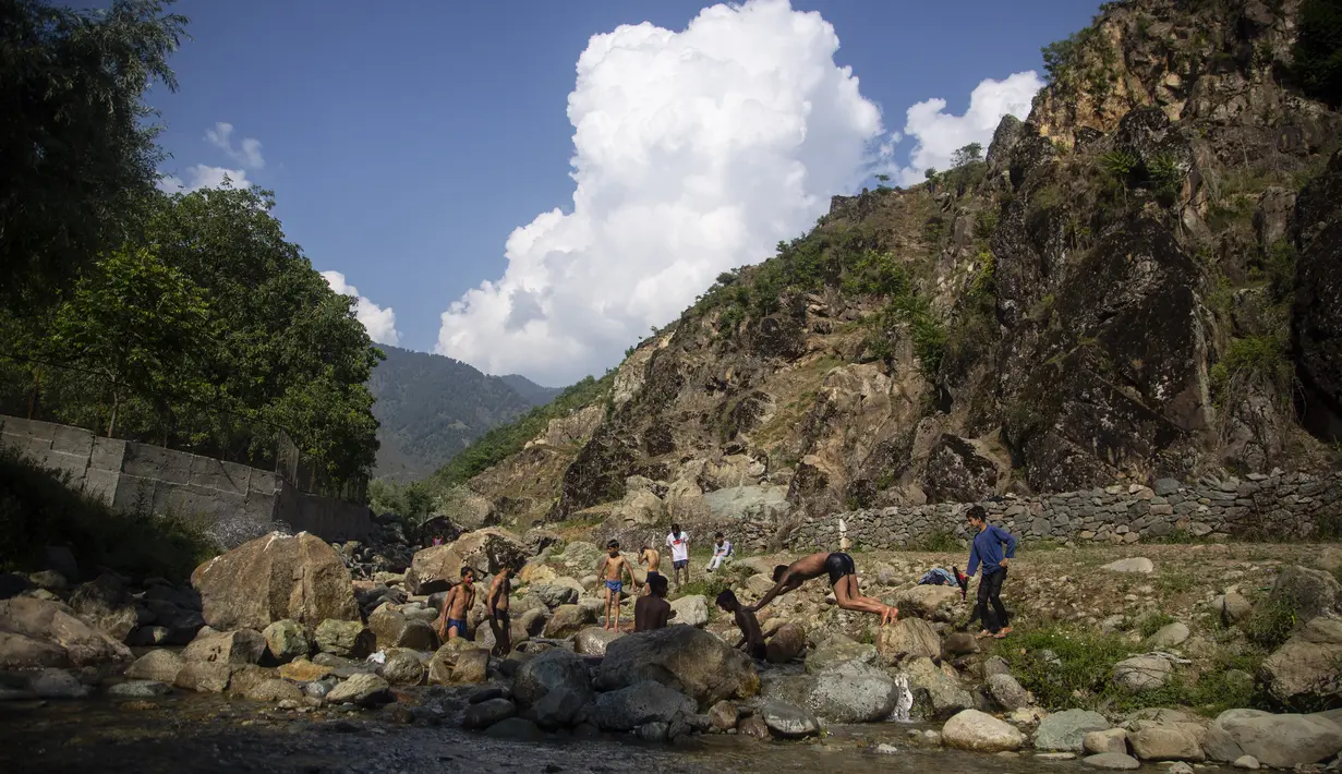 Pemuda Kashmir mendinginkan diri di sungai saat musim panas di pinggiran Srinagar, Kashmir yang dikuasai India (4/7/2021). Musim panas waktu yang tepat untuk menghabiskan waktu di ruang terbuka hijau. Seperti warga Kashmir menikmati musim panas dengan pergi ke sungai. (AP Photo/Mukhtar Khan)