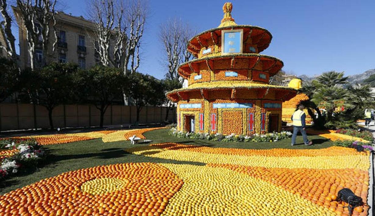 Seorang pria berjalan di dekat patung yang terbuat dari jeruk dan lemon menjelang festival Lemon di Menton, sebuah kota kecil di Perancis, Rabu (12/2/2015). (AFP PHOTO/Valery Hache)