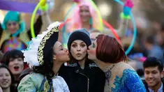 Aktris Mila Kunis (tengah) dicium oleh Amira Weeks (kiri) dan Jacques Berguig dalam sebuah parade di Cambridge (25/1). Mila Kunis dinobatkan sebagai "Woman of the Year" oleh kelompok teater Hasty Pudding. (AP Photo / Charles Krupa)