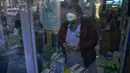 Warga tercermin di panel pintu saat mengantre untuk membeli obat di apotek di Beijing, Selasa (13/12/2022). Beberapa universitas di China mengatakan akan mengizinkan mahasiswanya menyelesaikan semester dari rumah dengan harapan mengurangi potensi wabah COVID-19 yang lebih besar selama kesibukan perjalanan Tahun Baru Imlek di bulan Januari mendatang. (AP Photo/Andy Wong)