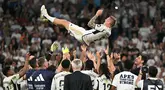 Gelandang Real Madrid #08 Toni Kroos terlempar ke udara oleh rekan satu timnya saat melawan Real Betis pada pekan ke-38 (pekan terakhir) La Liga 2023/2024 di Santiago Bernabeu, Minggu (26/5/2024). (JAVIER SORIANO / AFP)