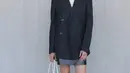 Gal Gadot tampil preppy dengan oversized jas hitam yang dipadukan turtleneck putih dan mini skirt abu-abu. Penampilannya dilengkapi dengan sepatu pantofel Prada hitam. [Dok/Prada]
