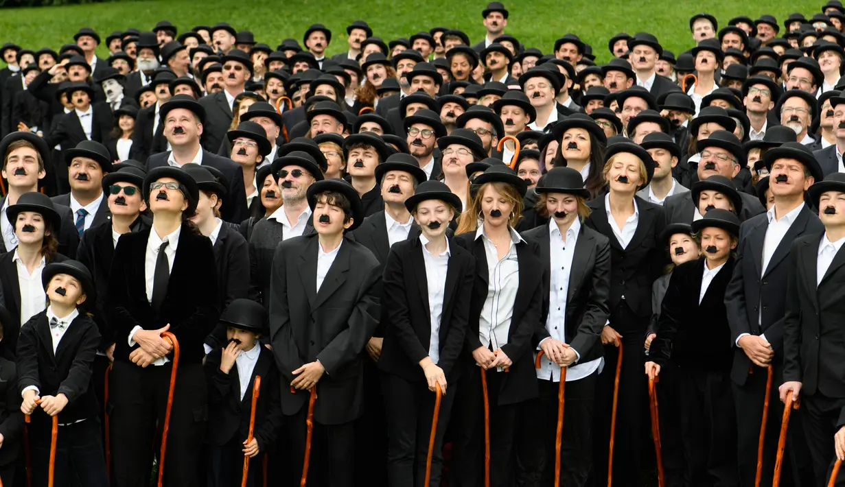 Sejumlah penggemar menggelar pertemuan dengan mengenakan kostum Charlie Chaplin di Corsier sur Vevey, Minggu (16/4). Mereka menirukan gaya Charlie Chaplin lengkap dengan topi, kumis kotak, dan tongkat kayu.  (Laurent Gillieron/Keystone via AP)