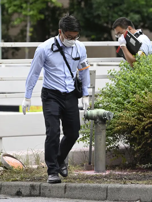 Polisi memeriksa tempat kejadian di mana seorang pria dilaporkan membakar dirinya, di dekat Kantor Perdana Menteri di Tokyo, Rabu, 21 September 2022. Kini, pria dan polisi dilarikan ke rumah sakit terdekat. Namun, belum ada kabar lebih lanjut mengenai kondisi mereka saat ini. (Kyodo News via AP)