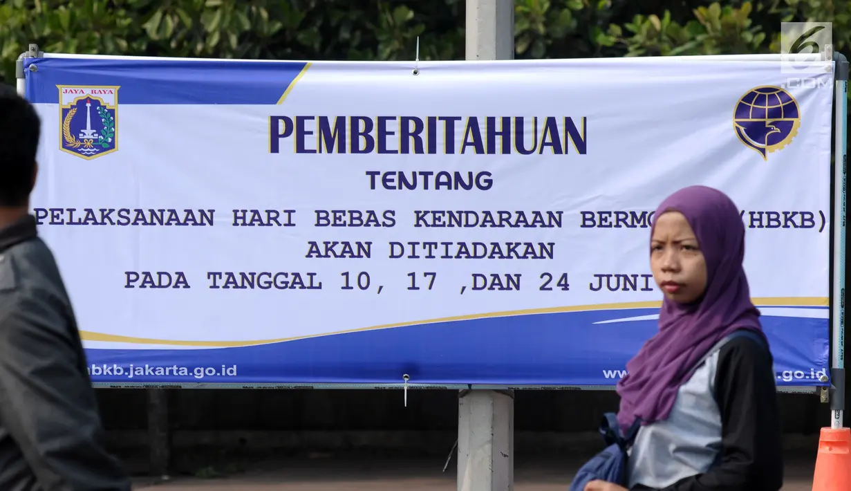 Warga melintasi spanduk pemberitahuan peniadaan pelaksanaan Hari Bebas Kendaraan Bermotor (HBKB) di sekitar Bundaran Hotel Indonesia, Jakarta, Minggu (3/6). Pelaksanaan HBKB akan ditiadakan pada 10, 17, dan 24 Juni 2018. (Liputan6.com/Helmi Fithriansyah)