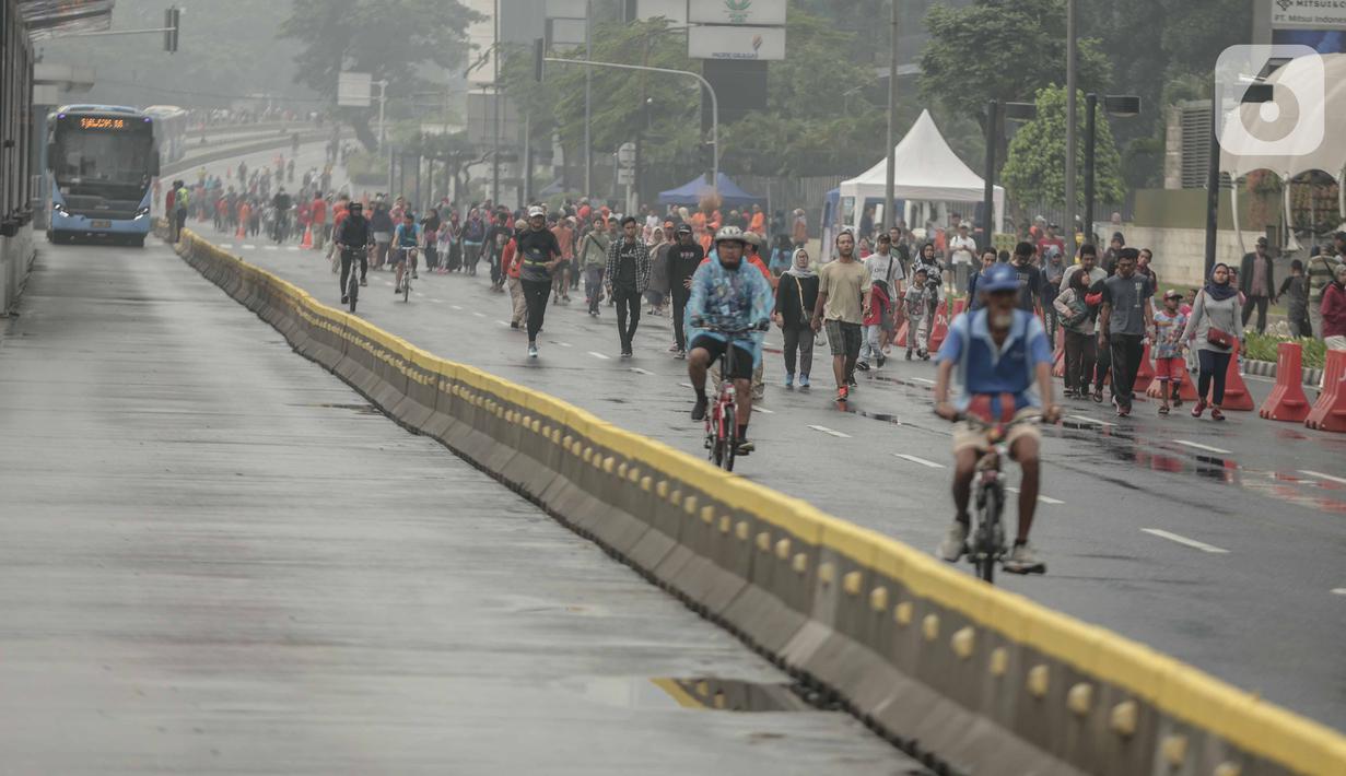 Warga beraktivitas saat car free day (CFD) di kawasan Bundaran HI, Jakarta, Minggu (29/12/2019). Kendati tidak seramai saat cerah, warga yang berlari, jalan santai, atau swafoto masih menjadi pemandangan di area CFD usai hujan mengguyur Jakarta. (Liputan6.com/Faizal Fanani)