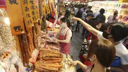 Warga mengenakan masker untuk mencegah penyebaran virus corona berbelanja untuk perayaan Tahun Baru Imlek di pasar Dihua Street di Taipei, Taiwan, Rabu (10/2/2021). Tahun Baru Imlek menurut kalender lunar akan berlangsung pada 12 Februari. (AP Photo/Chiang Ying-ying)