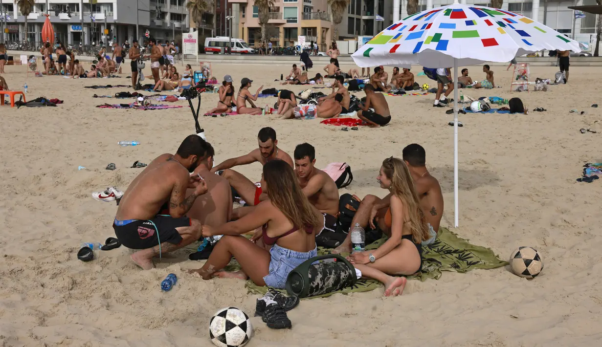 Orang-orang bersantai di pantai di kota pesisir Israel Tel Aviv (19/4/2021). Pemerintah Israel mencabut kewajiban memakai masker setelah 81 persen penduduk dewasa menerima vaksin Covid-19. (AFP/menahem kahana)
