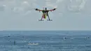 Pesawat tak berawak (drone) pendeteksi hiu berpatroli di atas para peselancar di Pantai Bilgola, utara Sydney, Australia, 10 Desember 2017. Drone ini dilengkapi sistem yang mampu mendeteksi predator bawah air dengan cepat dari udara. (PETER PARKS/AFP)