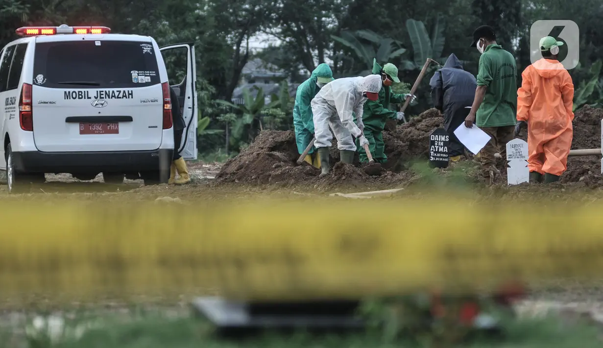 Garis batas polisi terlihat di dekat petugas saat proses pemakaman jenazah korban virus Covid-19 di TPU Tegal Alur, Jakarta, Kamis (25/6/2020). Menurut petugas makam TPU Tegal Alur, selama masa PSBB Transisi jumlah pemakaman jenazah dengan protap Covid-19 meningkat dibanding bulan lalu. (merdeka.com