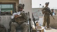 Seorang Marinir yang ditugaskan ke Unit Ekspedisi Marinir (MEU) ke-24 menenangkan seorang bayi selama evakuasi di Bandara Internasional Hamid Karzai, di Kabul, Afghanistan, Jumat (20/8/2021).  (Sgt. Isaiah Campbell/U.S. Marine Corps via AP)