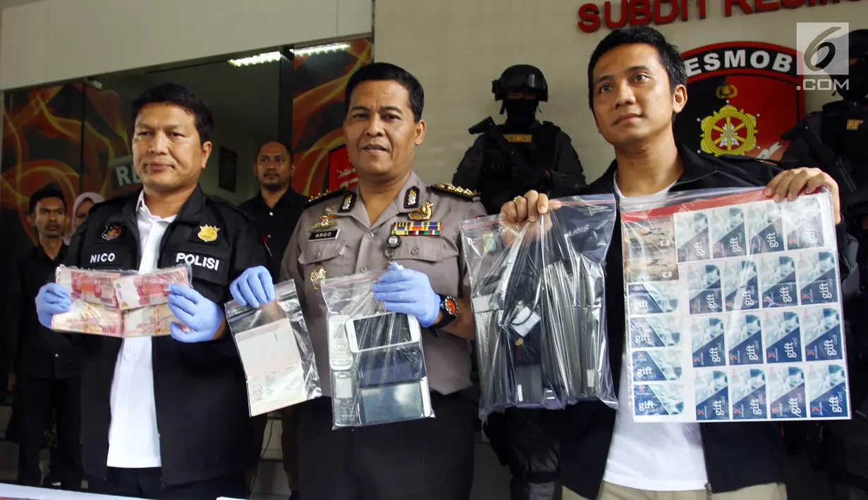 Kabid Humas Polda Metro Jaya Kombes Pol Argo Yuwono (tengah) menunjukkan barang bukti saat rilis tindak pidana pemalsuan atau pencurian data elektronik (skimming) di Polda Metro Jaya, Jakarta, Senin (19/3). (Liputan6.com/Arya Manggala)