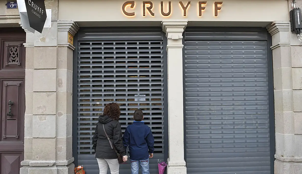 Pecinta sepak bola dunia berduka denagn meletakan bunga di depan Cruyff Store yang terdapat di Barcelona, Kamis (24/3/2016).  Bersama Ajax, Cruyff pernah meraih gelar Liga Champions sebanyak tiga kali. (AFP/Lluis Gene)
