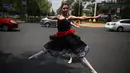 Balerina menampilkan tarian balet saat lampu merah di tengah jalanan Mexico City, 28 Juli 2018. Sejak pertunjukkan dimulai dua minggu lalu, para penari telah menarik perhatian fotografer, videografer, dan bahkan operator drone. (AP/Emilio Espejel)