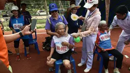 Seorang wanita lansia berusia 80 tahun, Duangpee Sansing (tengah) beristirahat usai memenangkan perlombaan sprint 400 meter dalam Elderly Games Nasional di Thailand (25/4). (AFP/Lillian Suwanrumpha)