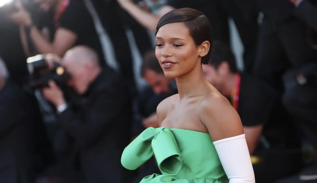 Taylor Russell berpose untuk fotografer setibanya di pemutaran perdana film 'Bones and All' selama Venice Film Festival ke-79 di Venesia, Italia (2/9/2022). Gaun tersebut terdiri dari siluet tebal, hiasan busur, jalur warna hijau zamrud dan dibuat dari kain satin yang mewah. (Photo by Joel C Ryan/Invision/AP)