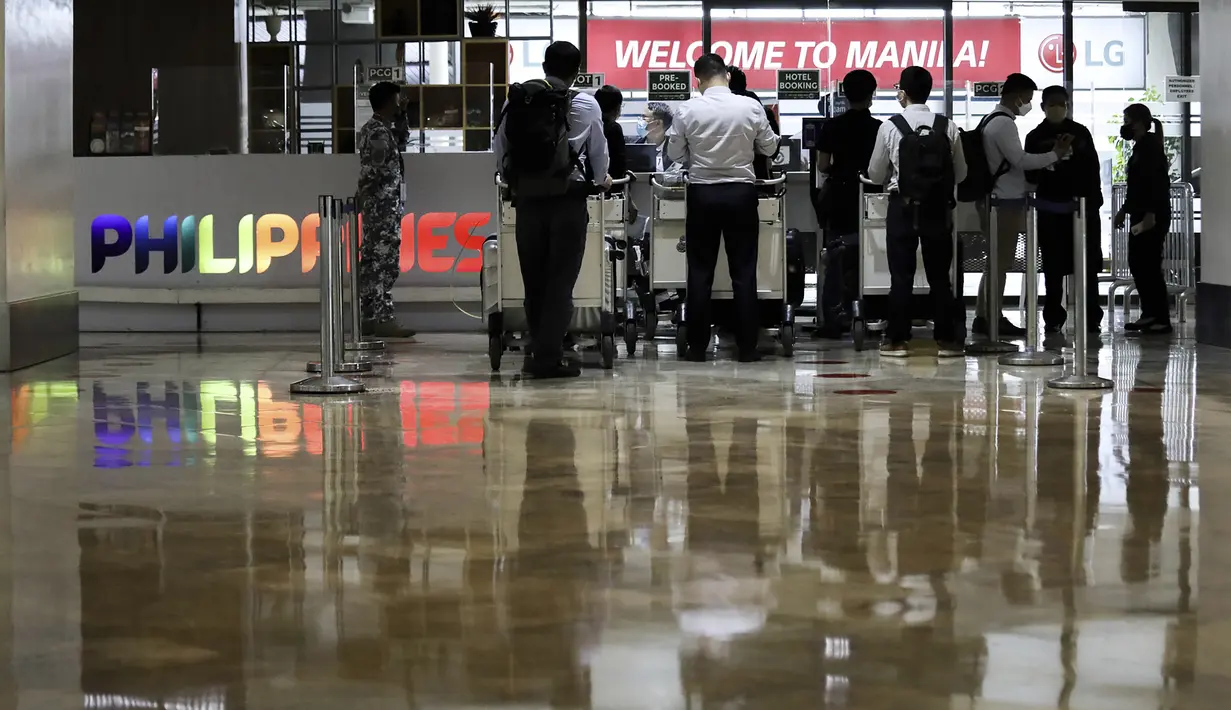 Petugas bandara memeriksa dokumen penumpang asing di konter saat mereka tiba di Bandara Internasional Manila, Filipina, Kamis (10/2/2022). Filipina mulai hari ini membuka kembali pintu bagi turis asing setelah hampir dua tahun menutup perbatasannya. (AP Photo/Basilio Sepe)