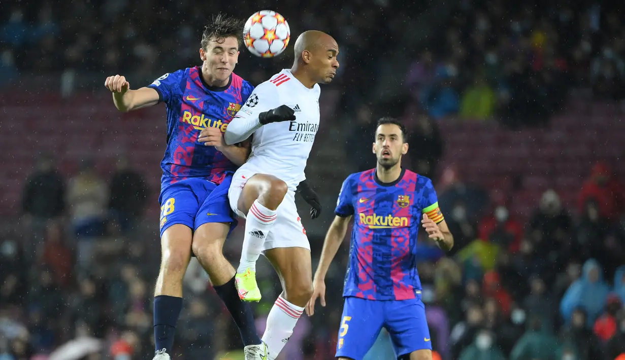 Gelandang Barcelona Nico Gonzalez (kiri) bersaing dengan gelandang Benfica Joao Mario pada matchday kelima Grup E Liga Champions di Camp Nou, Rabu (24/11/2021) dini hari WIB. Barcelona hanya mampu bermain imbang 0-0 kala menjamu Benfica. (LLUIS GENE / AFP)