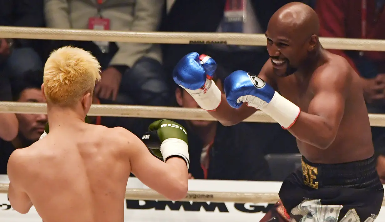 Petinju, Floyd Mayweather, berusaha memukul kickboxer, Tenshin Nasukawa, pada laga eksebisi di Saitama Super Arena, Saitama, Senin (31/1). Tanding dengan aturan tinju, Mayweather menang TKO di ronde pertama. (AFP/Toshifumi Kitamura)