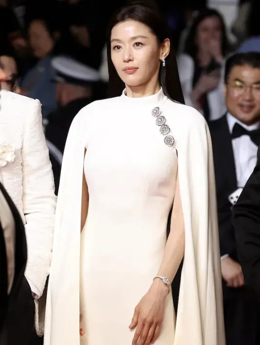 Gianna Jun kenakan cape dress dengan nuansa off white. Aksen kancing bermata berlian menambah statement tampilan yang menjanjikan.