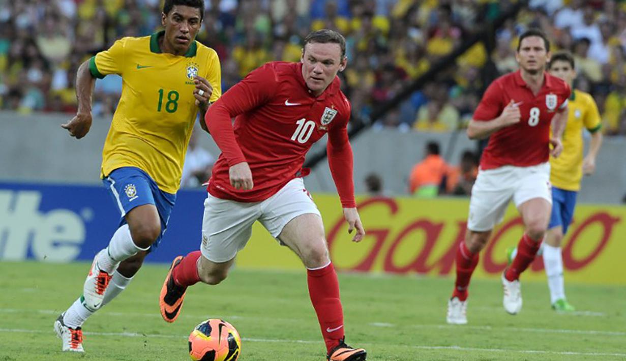 Wayne Rooney menggiring bola melewati pemain Brazil, Paulinho pada laga persahabatan di Stadion Maracana, Brazil, Minggu (2/6/2015). (AFP Photo/Yasuyoshi Chiba)