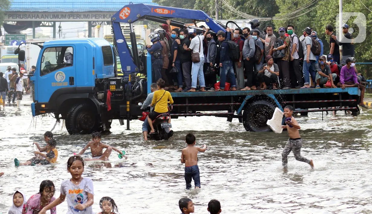 Pekerja kawasan Pelabuhan Nizam Zachman, Muara Baru menumpang kendaraan besar untuk melintasi genangan banjir rob, Jakarta, Jumat (5/6/2020). Banjir rob di Pelabuhan Muara Baru tersebut terjadi akibat cuaca ekstrem serta pasang air laut. (Liputan6.com/Helmi Fithriansyah)