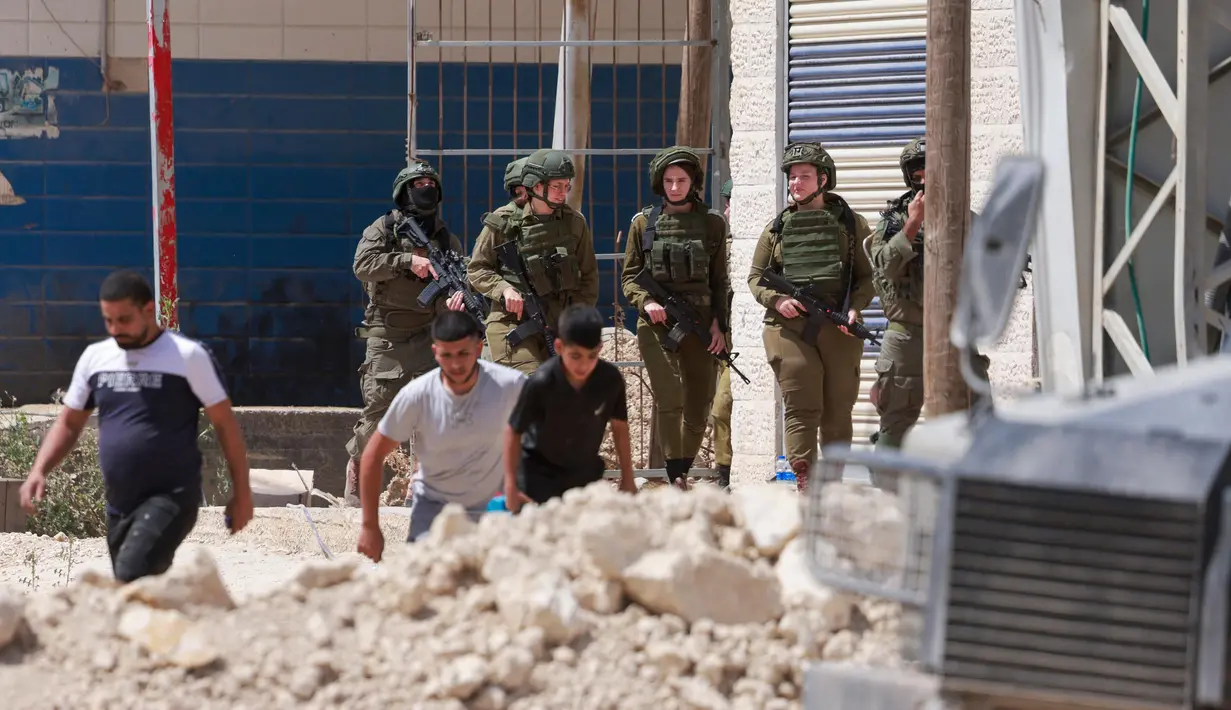 Tentara Israel berjaga-jaga ketika warga Palestina meninggalkan rumah-rumah mereka yang dijadwalkan akan dihancurkan di kamp pengungsi Tulkarem pada 26 Mei 2025. (Jaafar ASHTIYEH/AFP)